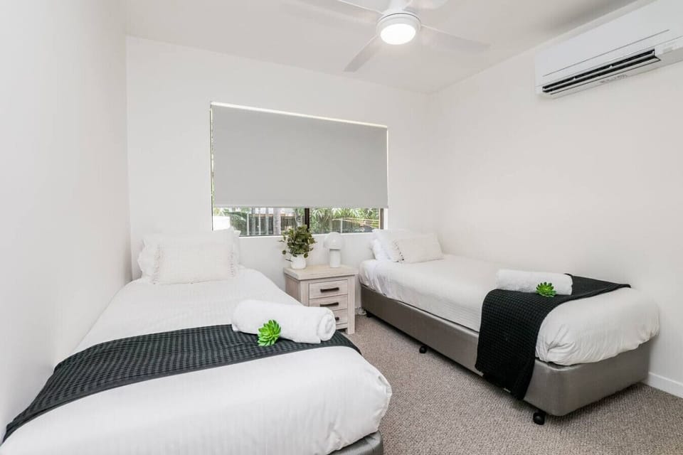 Bedroom with two single beds, dark runners, rolled towels, and succulent accents. Family‑friendly comfort in a modern setting.