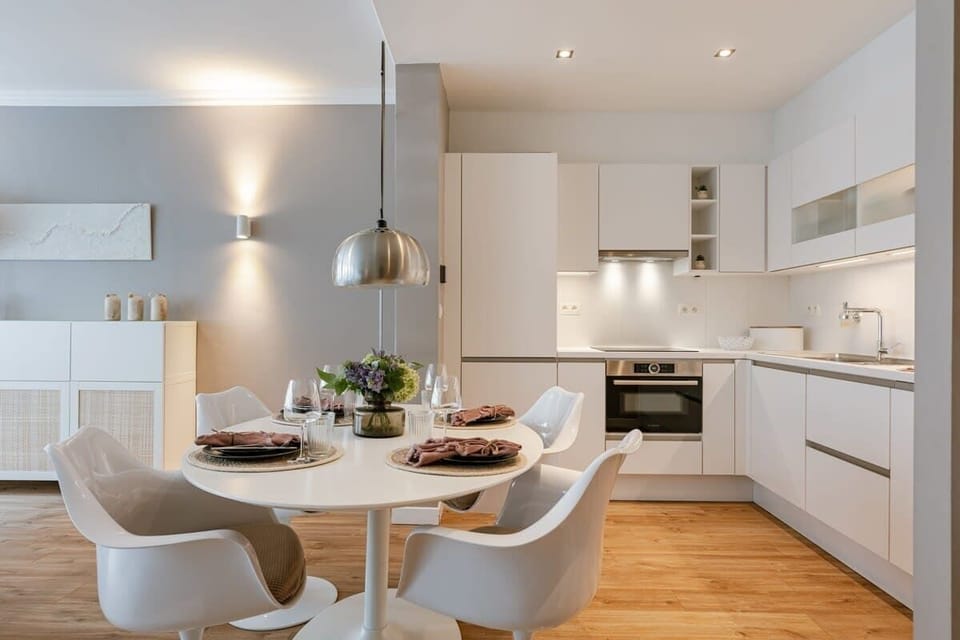 Modern kitchen and dining area with white cabinetry and a round table set for four.