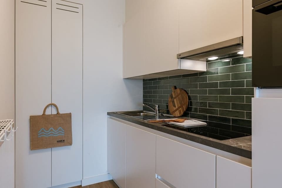 Compact kitchen with modern finishes and green tile backsplash.
