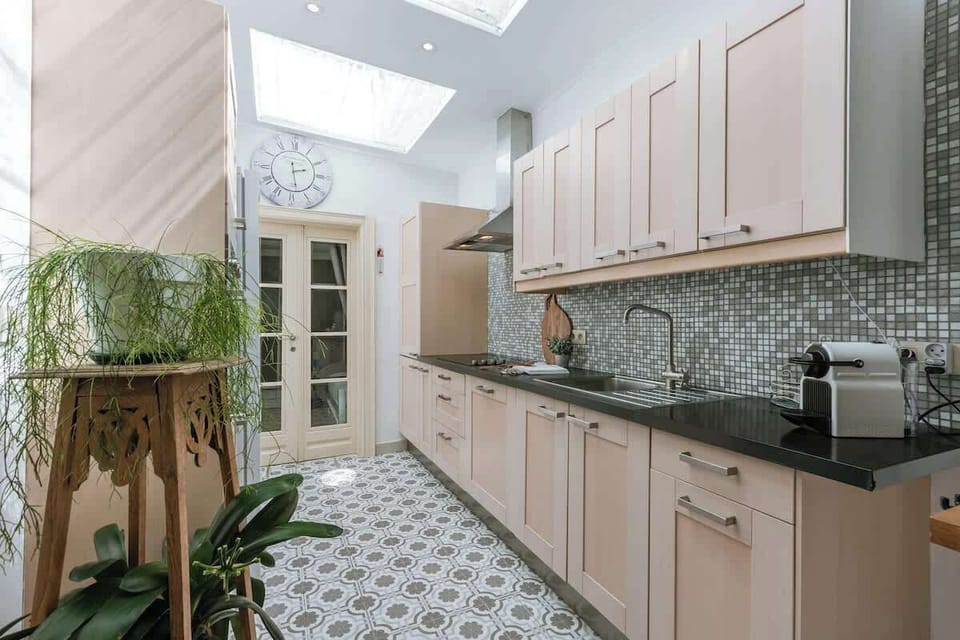 Bright kitchen with patterned tile floor and mosaic backsplash under skylights