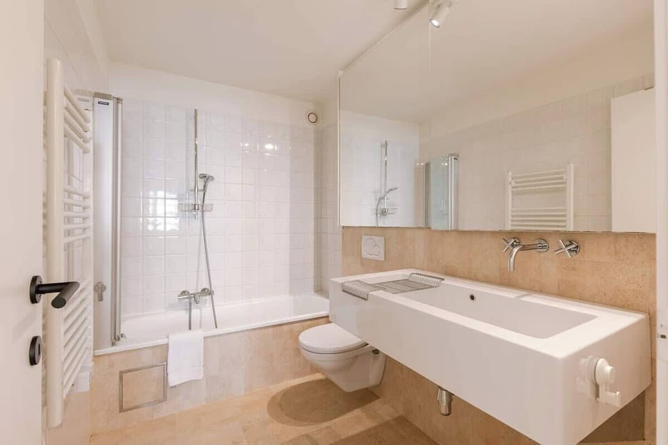 Modern bathroom featuring a bathtub with shower and a large wall mirror.