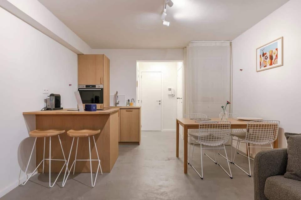 A bright, open-concept room designed for both relaxation and rest, featuring a large flat-screen TV and a comfortable sofa.