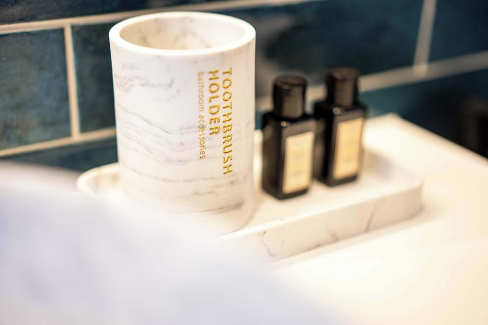 Marble toothbrush holder and toiletries on a bathroom sink with blue tile backsplash