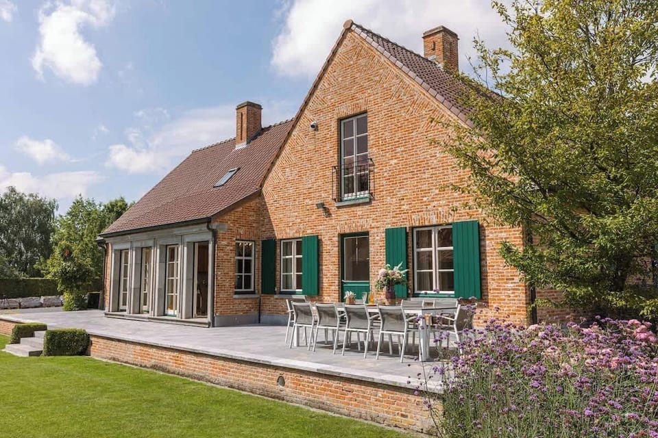Spacious brick house with a large outdoor dining terrace and garden views.