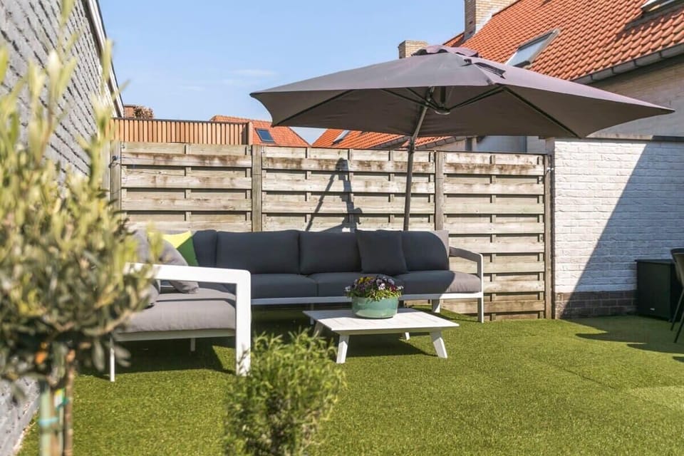 Modern outdoor seating area with a large umbrella on artificial grass