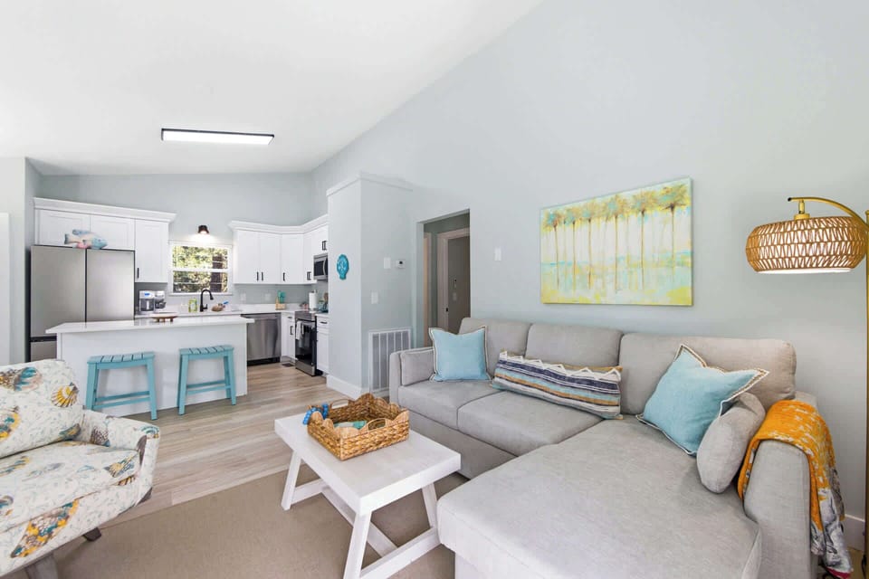 Bright open-concept living room with modern kitchen, comfortable seating, and natural light