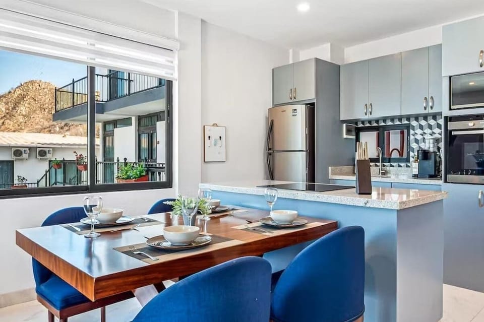 Dining area w/ table setup next to bright modern kitchen