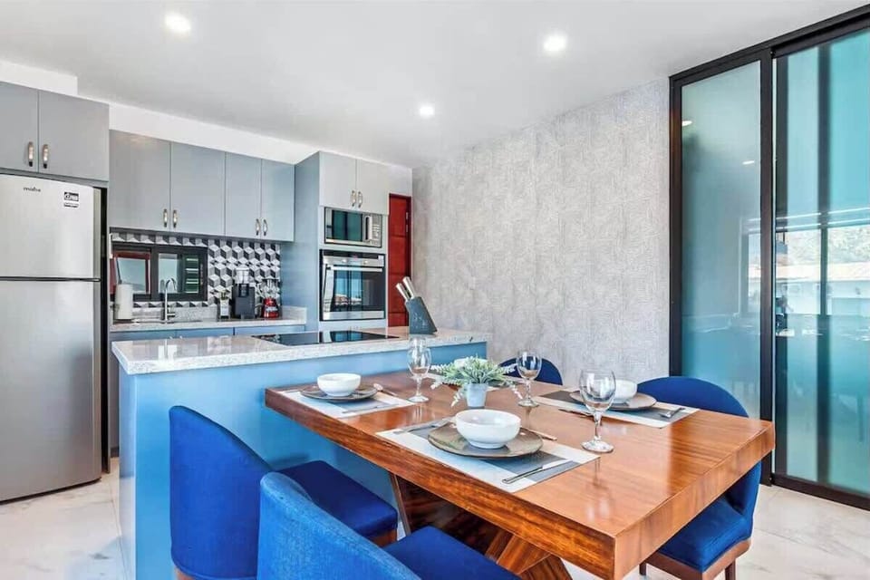 Dining table set for meals beside a sleek open kitchen