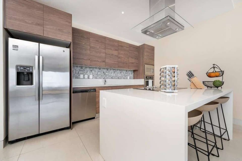 Modern kitchen w/ sleek cabinetry, island seating & stainless fridge