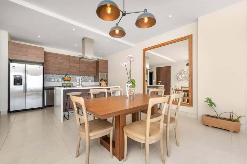 Dining area w/ wooden table set beside an open, modern kitchen