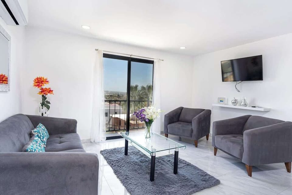 Bright living room w/ sofa seating, TV & large sliding doors opening to fresh air