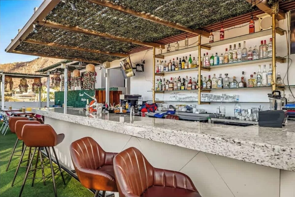 Shared open-air bar w/ rustic wood details & shaded seating for laid-back drinks