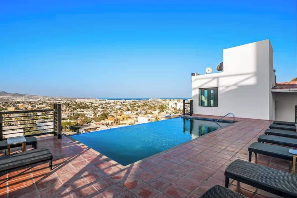 Shared sunlit rooftop pool w/ loungers and expansive views stretching to the horizon