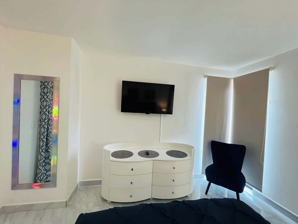 Airy bedroom w/ tiled floors, glass shower & bold accent bedding