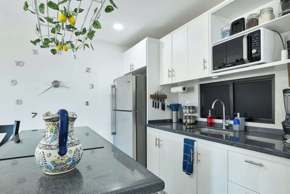 Compact kitchen w/ sleek countertops, open shelving, and all essentials within reach