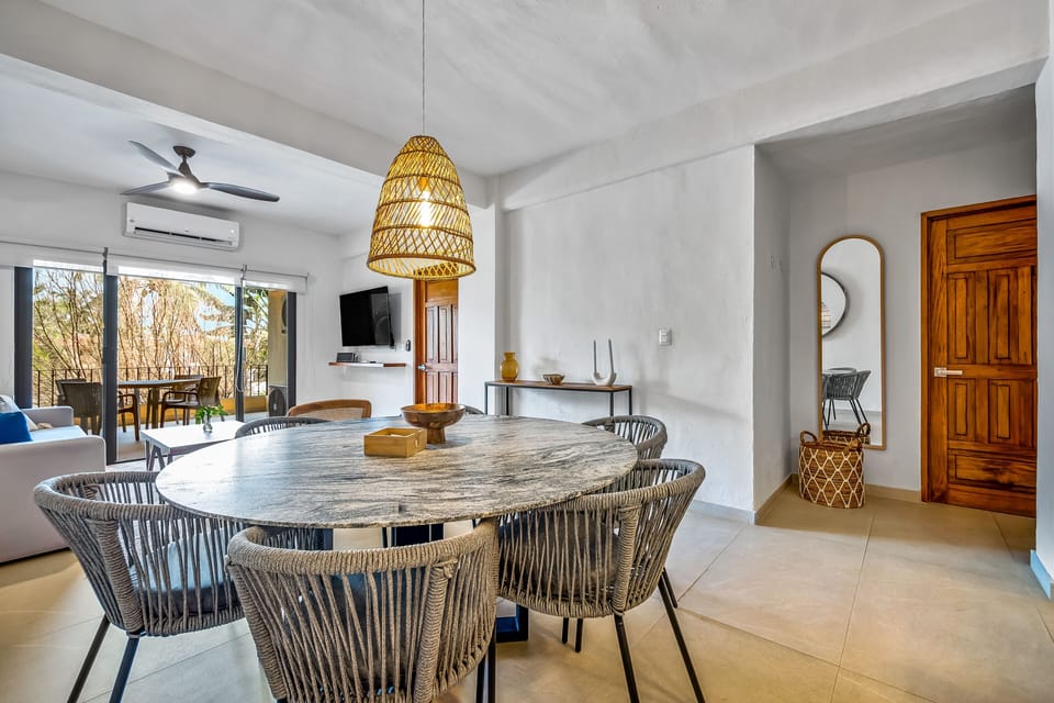 Angle showing the dining setup adjacent to the apartment entry and a full-length mirror.