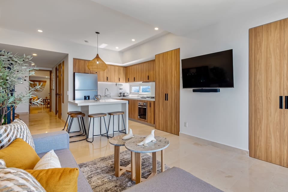 Bright coastal living space with floor-to-ceiling ocean views, designer décor, and seamless access to a private balcony perfect for sunset dining and relaxing by the sea.
