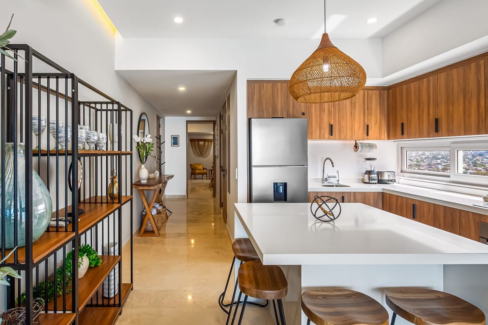 Stylish fully equipped kitchen with sleek wood cabinetry, spacious island seating, premium appliances, and an airy open-concept layout.