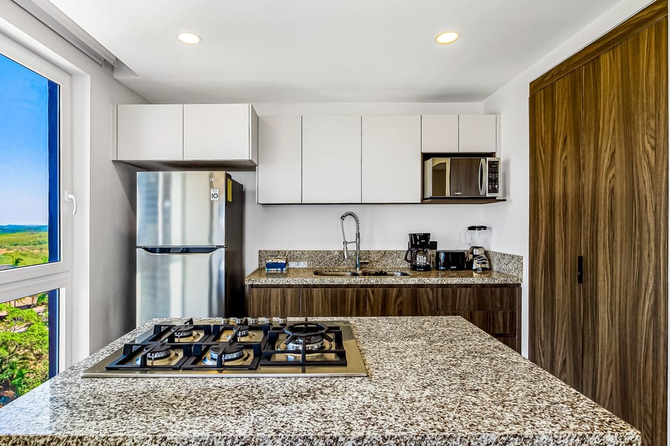 This modern cooking space is loaded with premium amenities, including a stainless steel refrigerator, microwave, and ample cabinet storage.