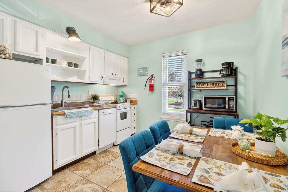 Your beach-themed kitchen awaits with full appliances, coastal charm, and a welcoming dining table set for memorable meals with loved ones.
