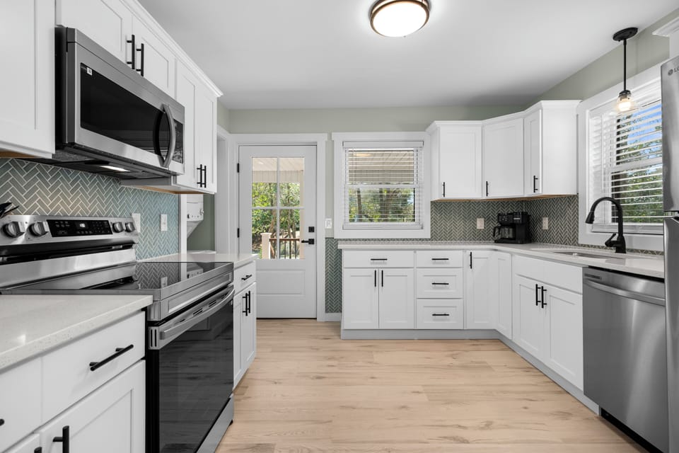 Your fully equipped kitchen awaits with modern appliances, elegant white cabinetry, and stylish tile backsplash for memorable meal prep.
