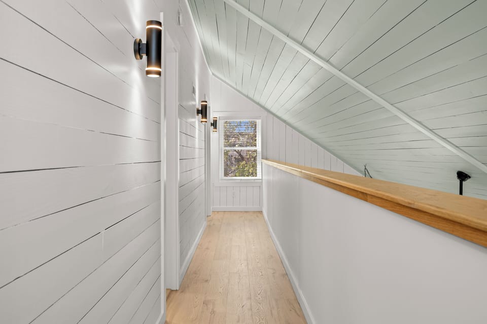 Your bright hallway features warm wood floors and modern lighting, leading to cozy nooks where you can unwind and enjoy peaceful tree views.
