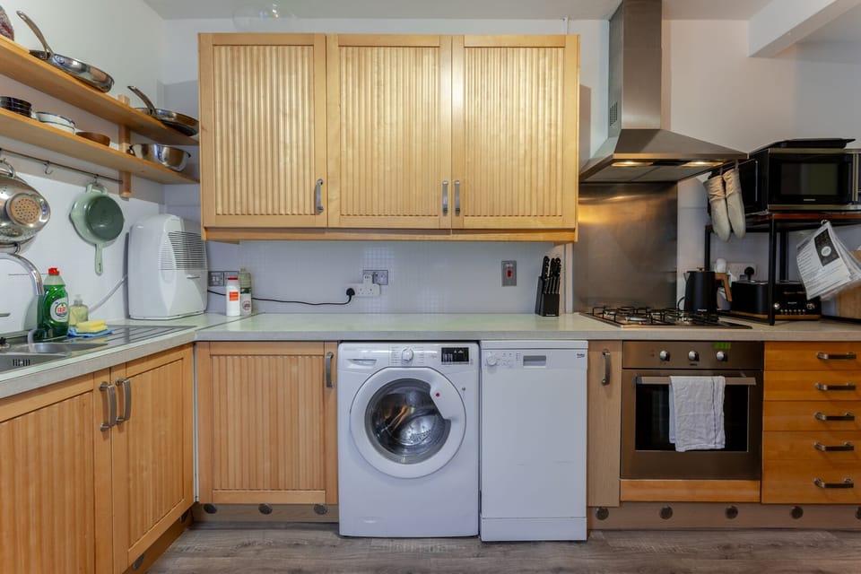 A fully equipped kitchen features a washing machine, dishwasher, toaster, kettle, microwave, and a dining table for shared meals