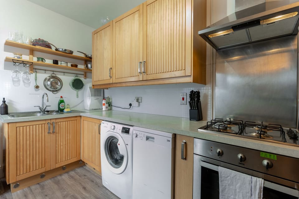 A fully equipped kitchen features a washing machine, dishwasher, toaster, kettle, microwave, and a dining table for shared meals