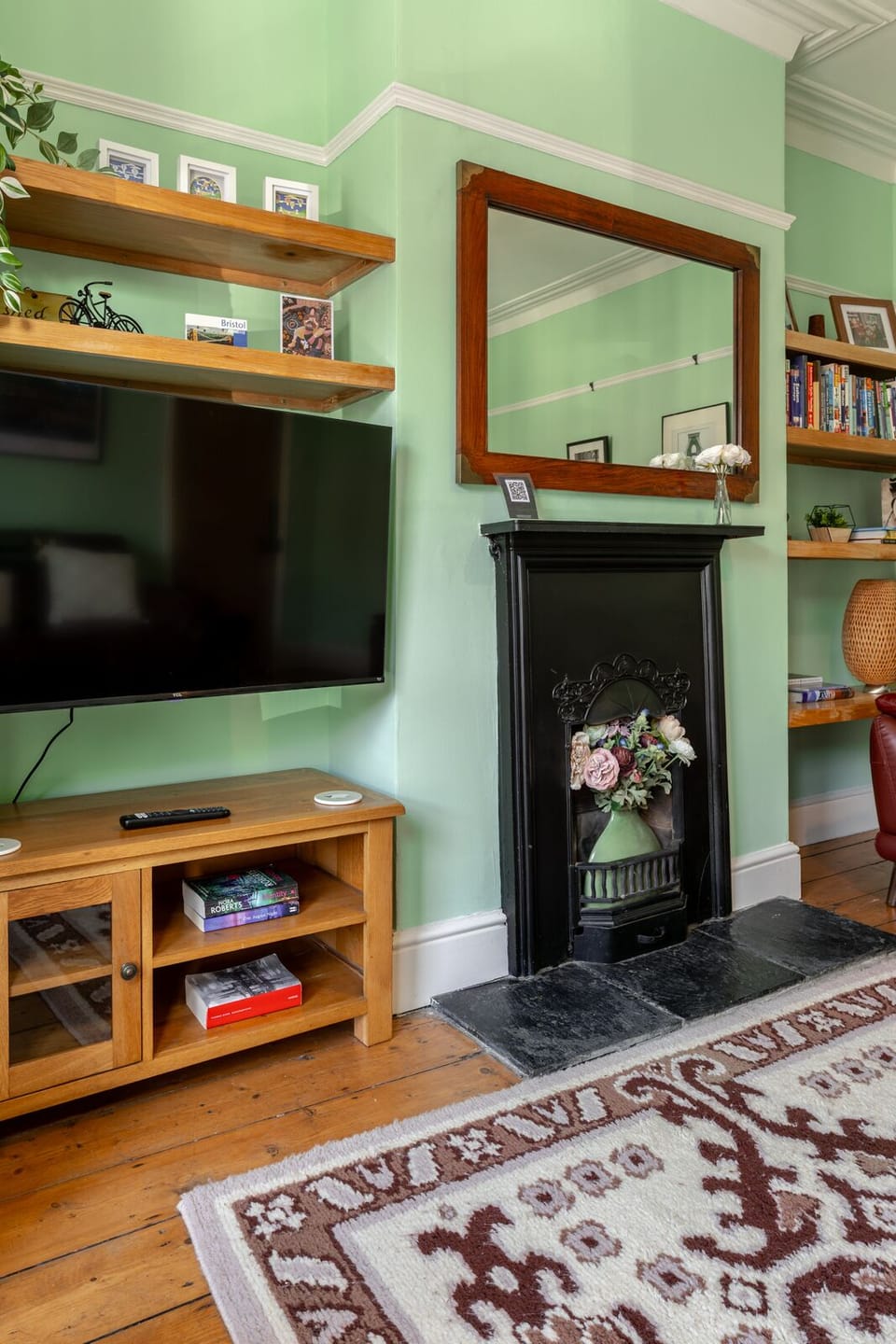The living room features comfortable sofas, books, and a TV for relaxing evenings