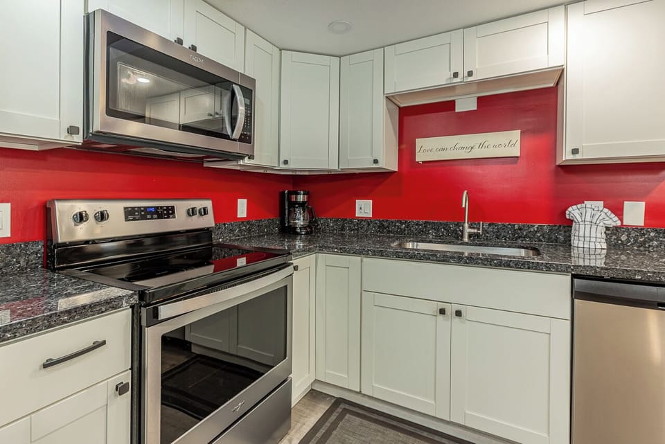 Your fully-equipped kitchen features vibrant red accents, granite countertops, and modern appliances for preparing memorable meals together.