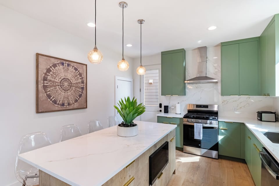 Bright chef’s kitchen with a spacious island and seating, sleek finishes, and premium appliances—designed for cooking, gathering, and entertaining comfortably as a group.