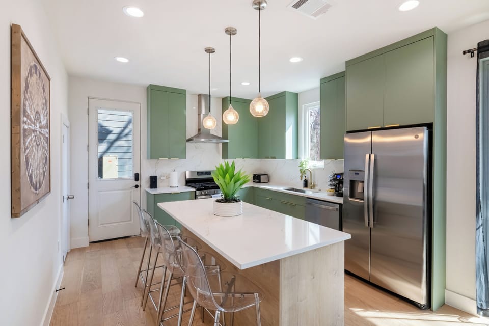 Sun-filled chef’s kitchen featuring a spacious island with seating, sleek cabinetry, and premium appliances—designed for cooking, gathering, and entertaining together in style.