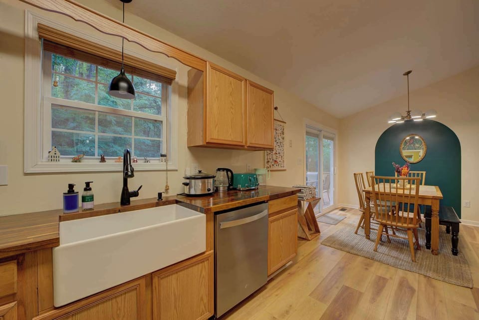 Farmhouse sink by a big window—nice for rinsing up while you watch the woods outside.