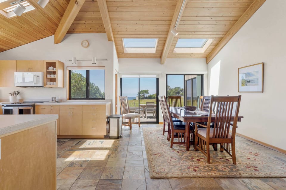 The open layout flows from kitchen to dining with skylights above and ocean views ahead, making the main living area bright and welcoming.