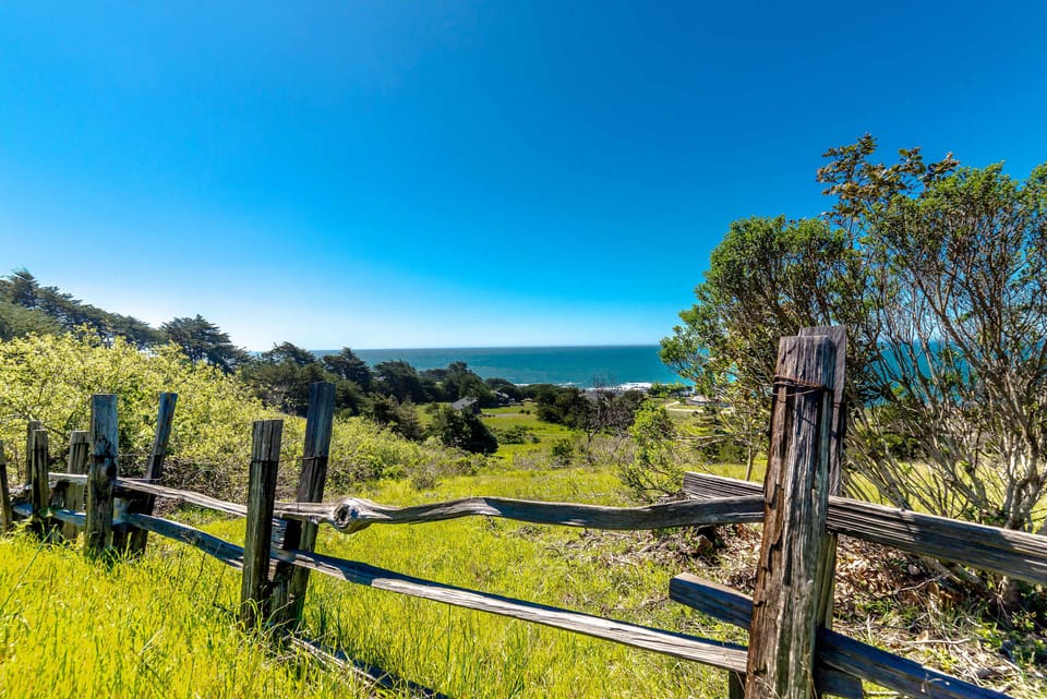 Gaze out over the stunning coastline, where a rustic fence frames the view, drawing you into the breathtaking landscape.
