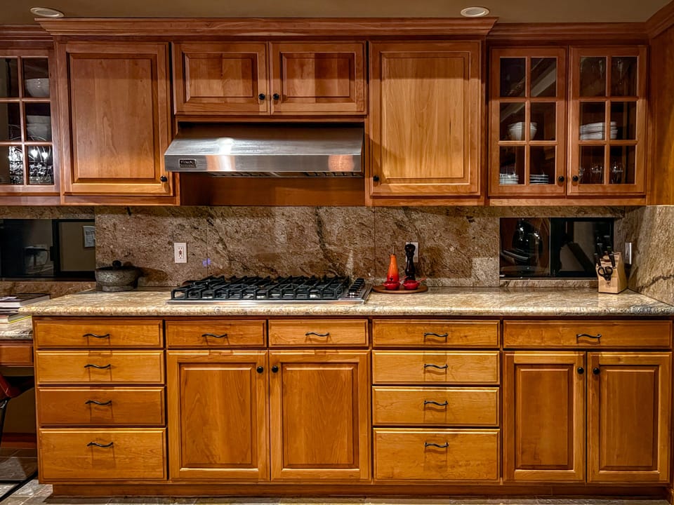Five-burner Viking gas cooktop under a stainless hood — granite counters and glass-front cabinets keep everything within reach.