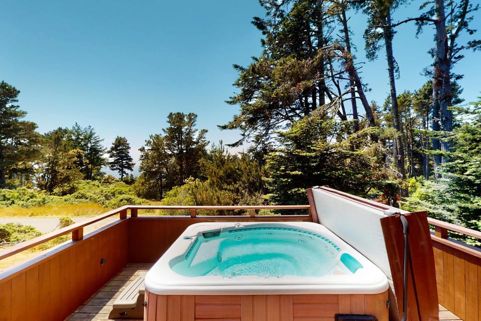 Soak in the hot tub while surrounded by serene nature, a perfect retreat after a day of exploring the stunning coastline.