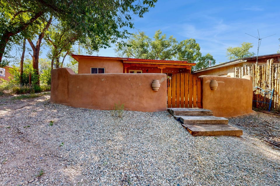 Arrive to a classic Taos adobe framed by mature cottonwoods