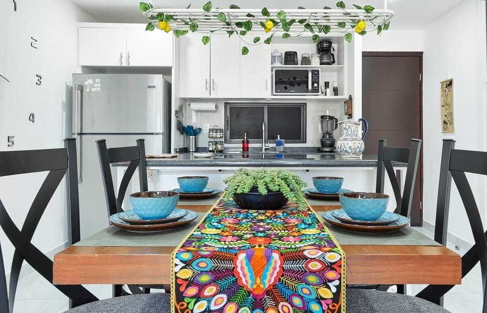 Stylish kitchen dining table w/ colorful textiles & natural light