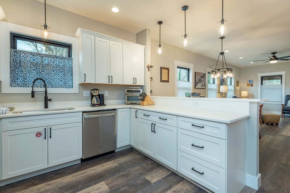 Well-equipped kitchen with stainless steel appliances, dishwasher, kettle, and drip-style coffee maker.
