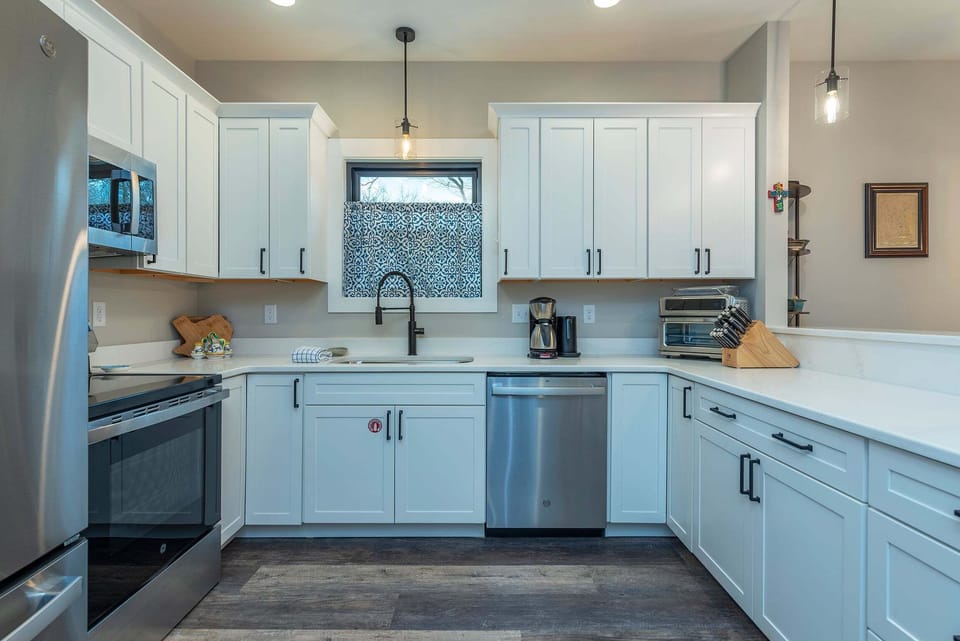 Well-equipped kitchen with stainless steel appliances, dishwasher, kettle, and drip-style coffee maker.