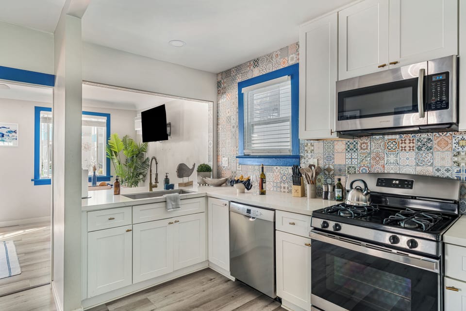 Modern kitchen featuring stainless steel appliances and custom tile backsplash.