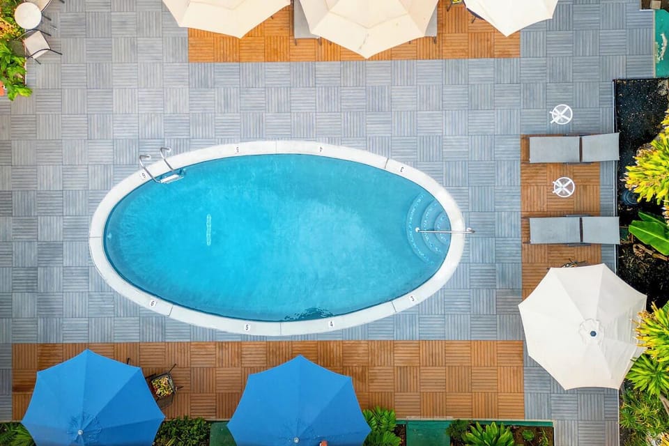 Dive into a sunlit pool oasis with loungers and shade.