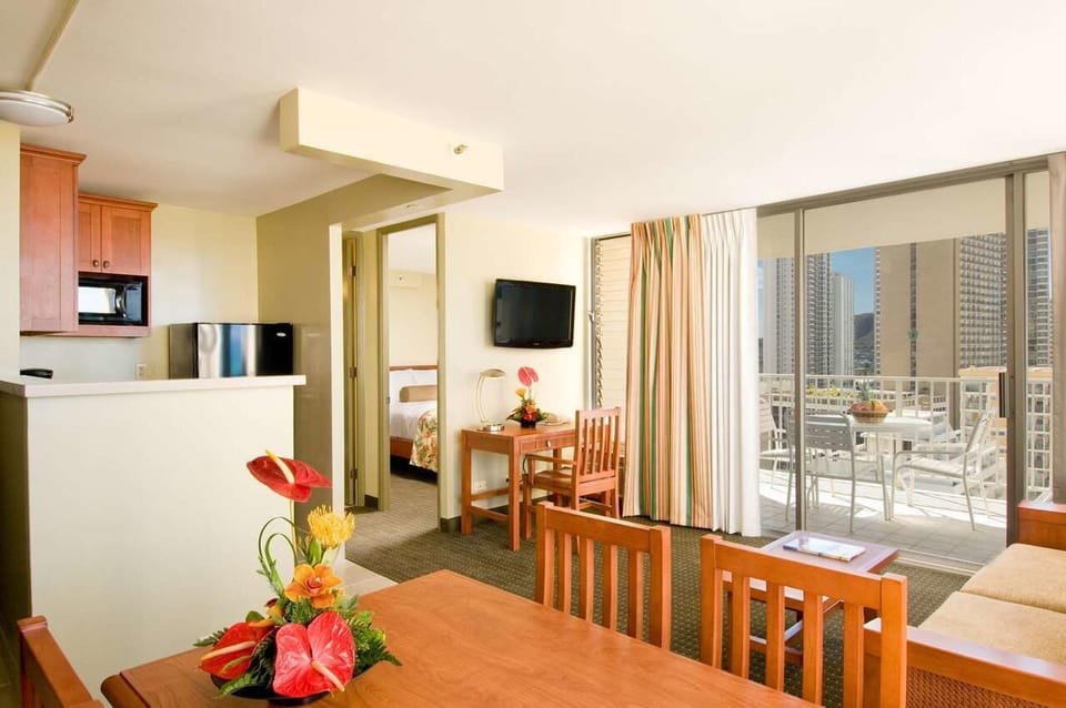 Gather for meals at the table beside sunlit balcony doors.