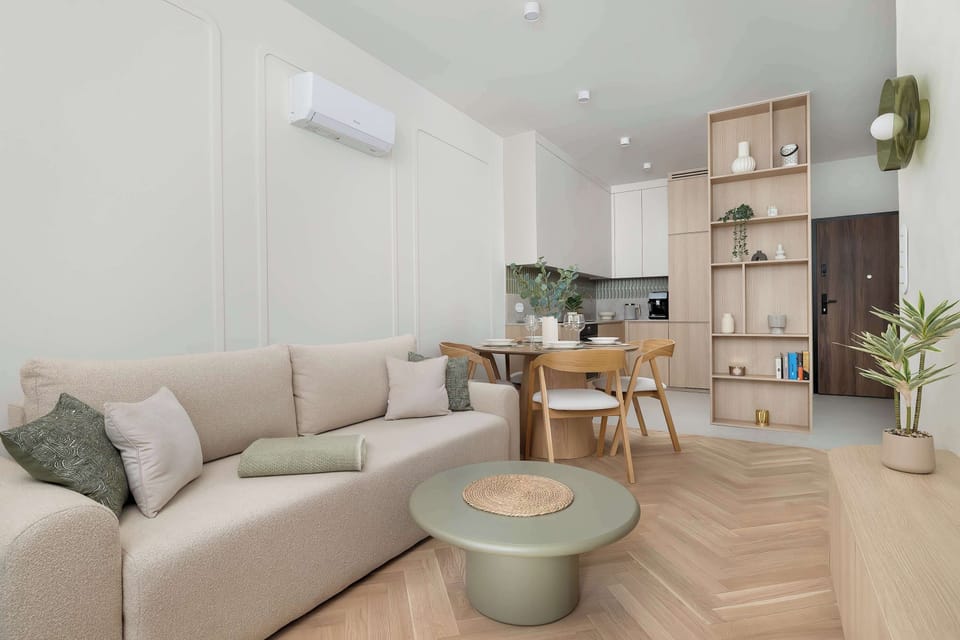 A cohesive living and dining space demonstrates the integrated layout of the apartment. The neutral color palette and warm wood textures create a sophisticated and welcoming home environment.