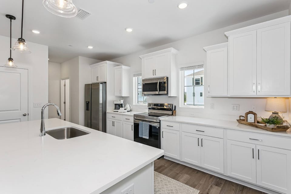 The gourmet kitchen features stainless appliances, quartz countertops, soft close shaker style cabinets and an expansive island.