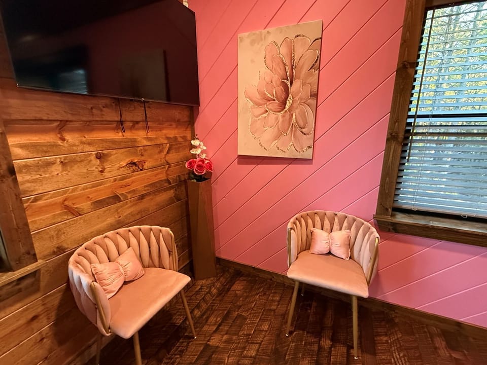 Settle into these plush chairs and feel the charm of this cozy pink retreat. With warm wood tones and soft natural light, you'll find the perfect spot to unwind after a day of exploring.