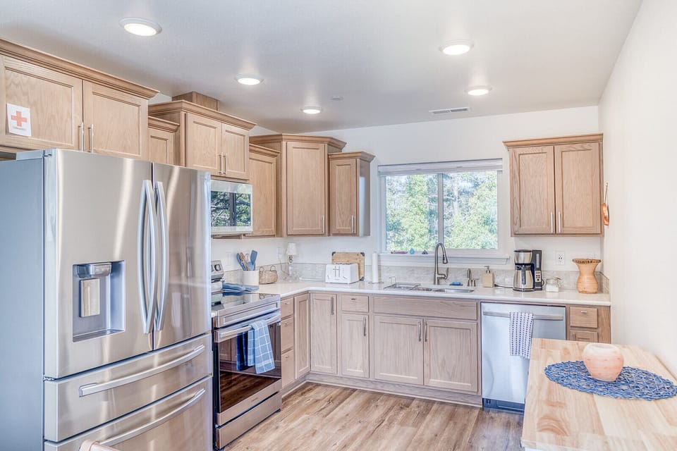 Your fully equipped kitchen awaits with stainless steel appliances, granite counters, and a peaceful garden view through the window.