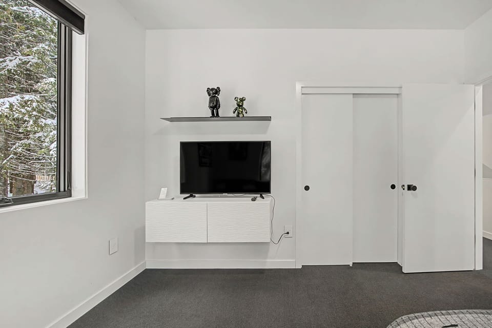 Unwind in your sleek modern living space with wall-mounted TV and crisp white decor creating a serene atmosphere.