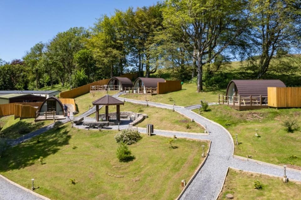 Stunning aerial view of four pods—Laurels, Treetops, Cwtch, Hafan Glyd—with a six-seat jacuzzi.